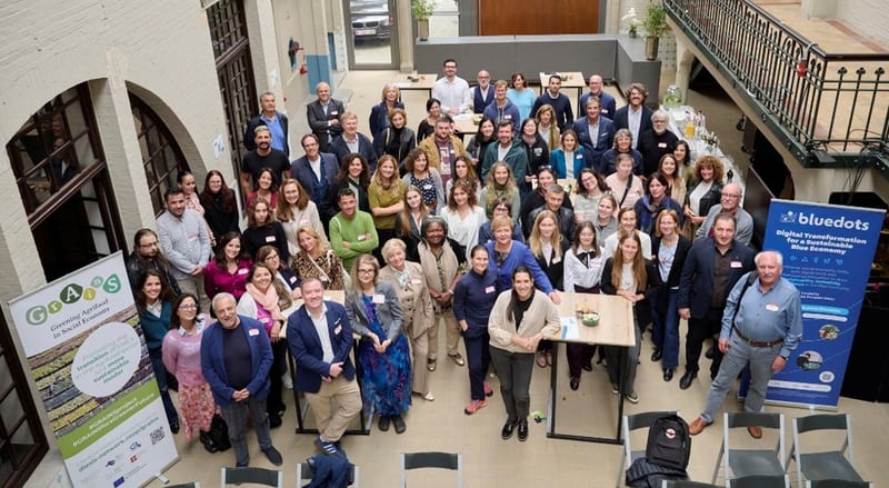 Group photo of event participants in a Brussels hall beside a Blue Dots banner on blue economy digital transformation