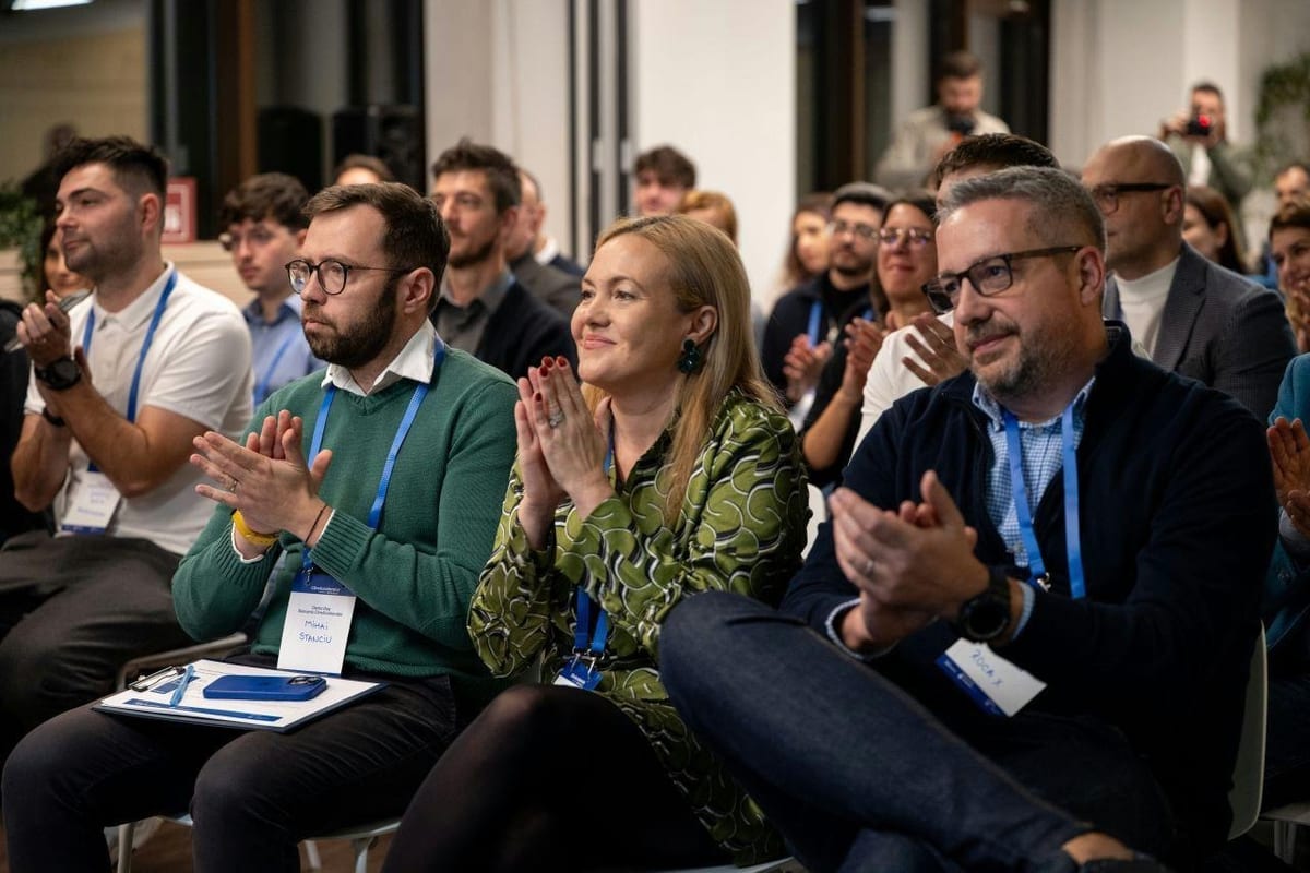 Seated audience members with lanyards applauding at Romania ClimAccelerator Demo Day 2025