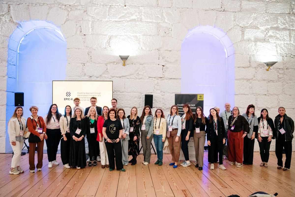 Large group of women-led startup founders and organisers posing beside an EPIC-X screen at SIM Conference 2026 in Porto