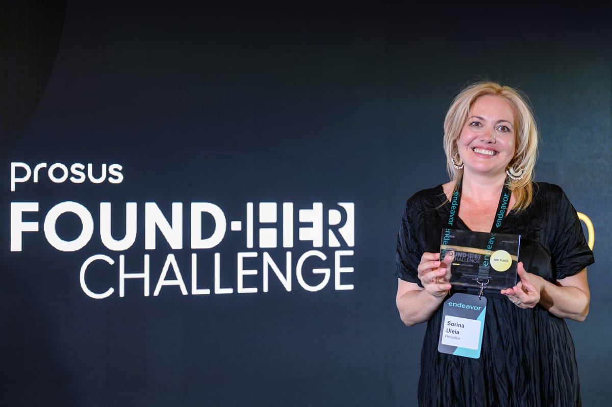 Woman with a badge reading Sorina Uleia holding a 3rd Place award in front of a Prosus Found-Her Challenge backdrop